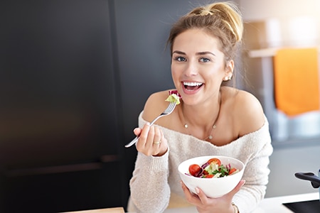 Beautiful Smiling Woman Eating Fresh Organic Vegetarian Salad In Modern Kitchen