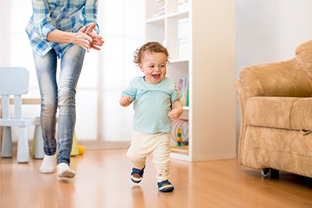 Baby boy have a fun running in living room with his mother